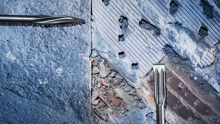 鑿子鑿穿粗糙的混凝土和磚牆。