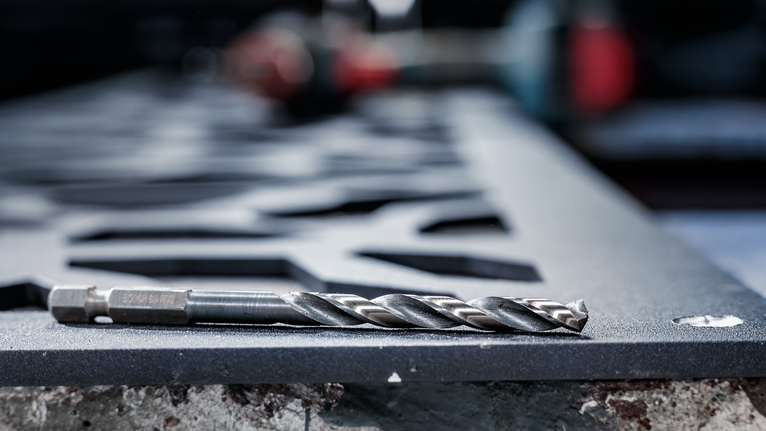 金屬鑽頭放在車間切割的鋼板上。