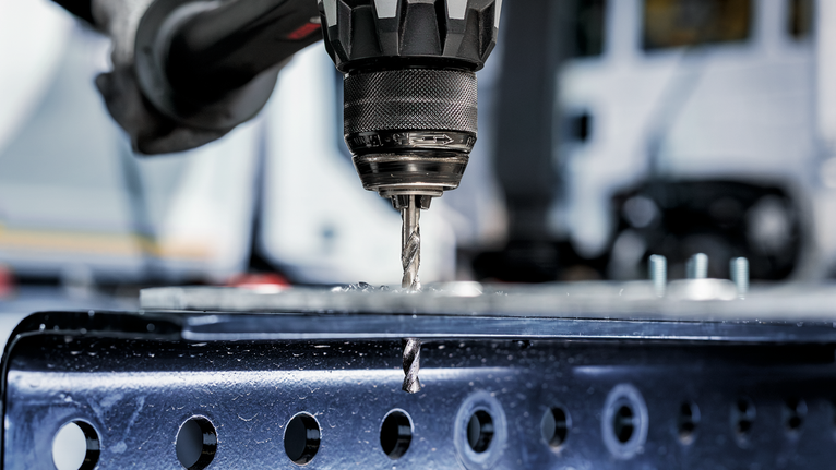 在工業環境中，鑽頭在金屬表面上鑽孔。