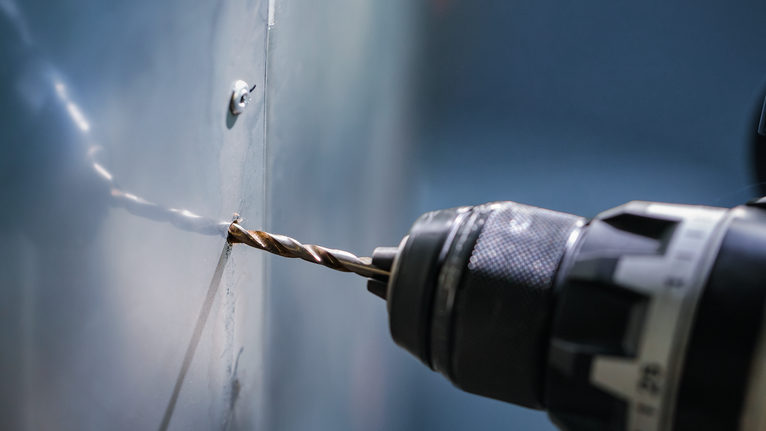 電鑽在金屬板上鑽孔。