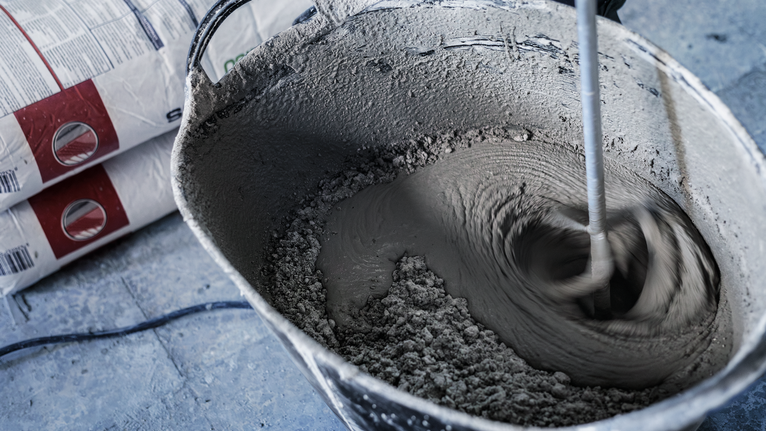 建築工地上，攪拌槳將水泥倒入桶中。