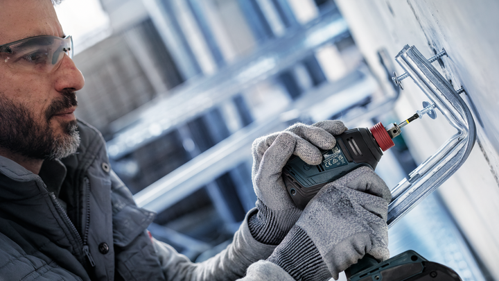 配戴安全設備的人員正在鑽入金屬壁支架。