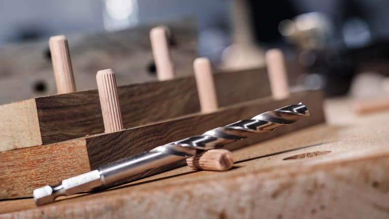 鑽頭和木釘排列在木製工作台上。