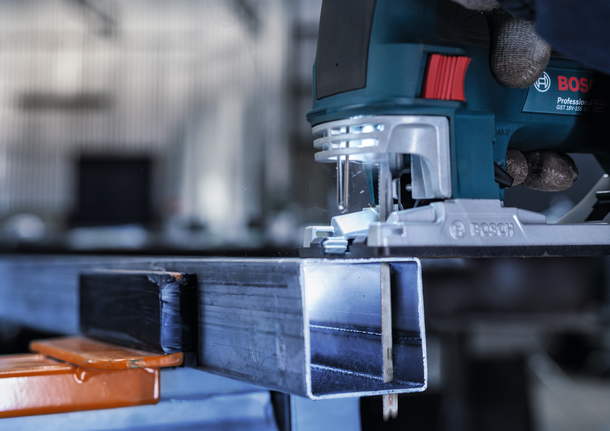 配戴安全設備的人員引導曲線鋸切割金屬梁。