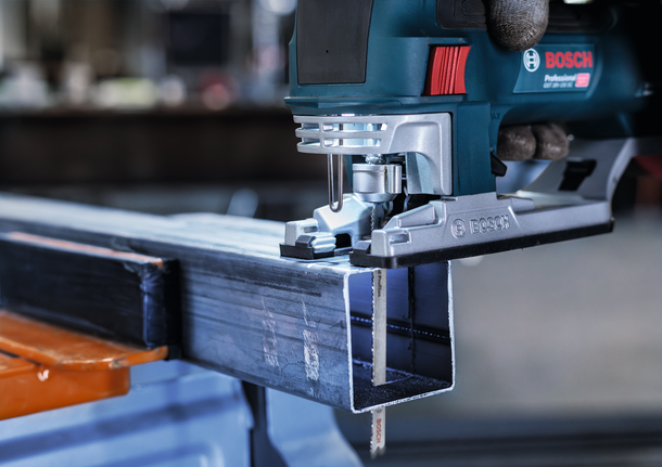 配戴安全設備的人員用曲線鋸切割金屬梁。