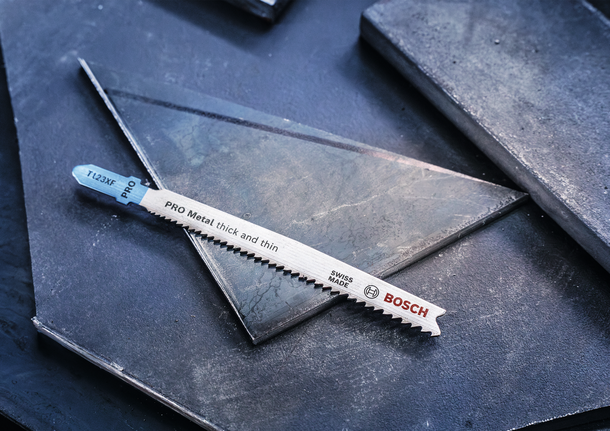 PRO Metal thick and thin T123XF 線鋸片,100 mm,3 件 金屬拼圖刀片放在深色金屬板上。