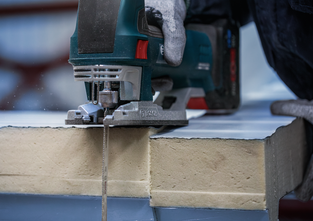 配戴安全設備的人員用曲線鋸切割絕緣板。