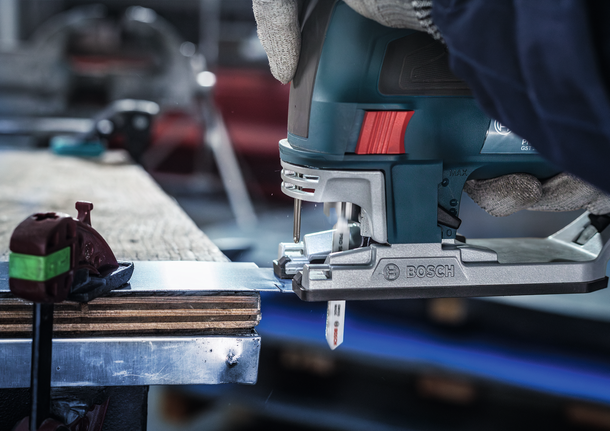 配戴安全設備的人員用曲線鋸切割金屬板。