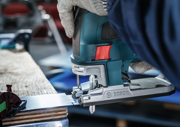 配戴安全設備的人使用曲線鋸切割金屬板。