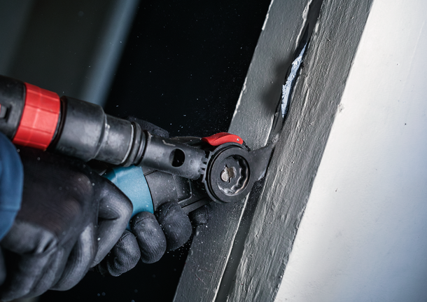 配戴安全設備的人員使用電動工具切割油漆表面。