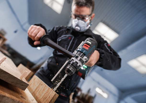 配戴安全設備的人員在室內鑽木頭。