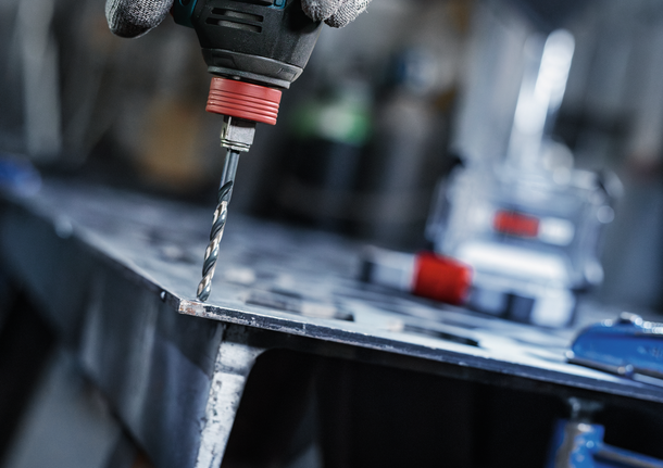 配戴安全設備的人員在金屬板上鑽孔。