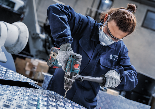 配戴安全設備的人員正在鑽入金屬板。