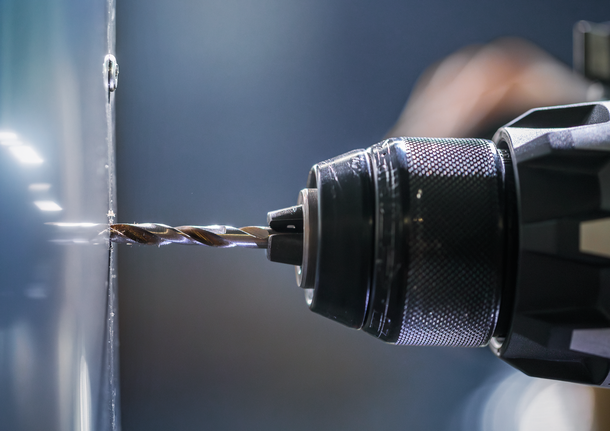 電鑽在金屬表面鑽孔。