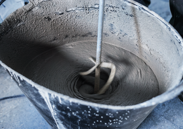 攪拌工具在一個黑色的大桶子裡攪拌水泥。