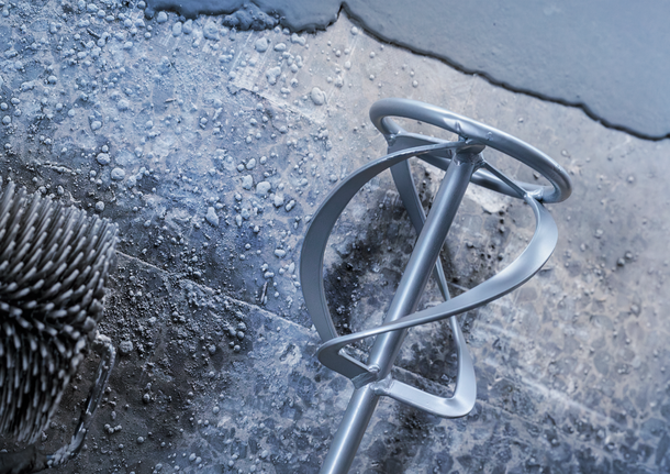 在濕潤的紋理混凝土表面上塗漆滾筒和攪拌槳。