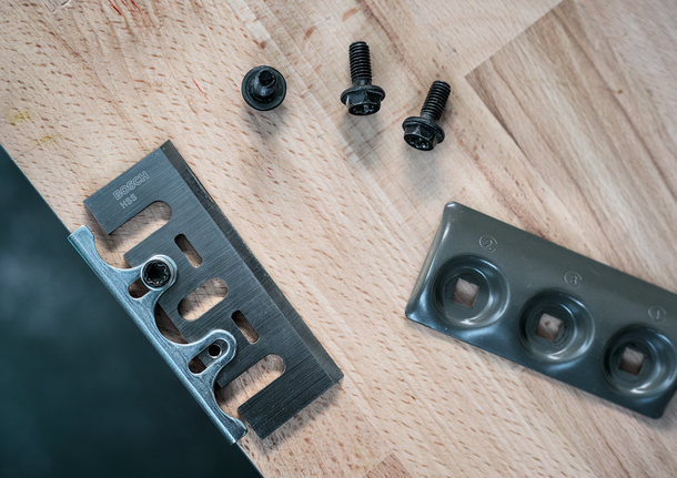 金屬刀片、緊固螺絲和安裝板排列在木質表面上。