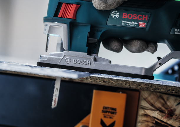 一名佩戴安全設備的人使用曲線鋸切割木板。