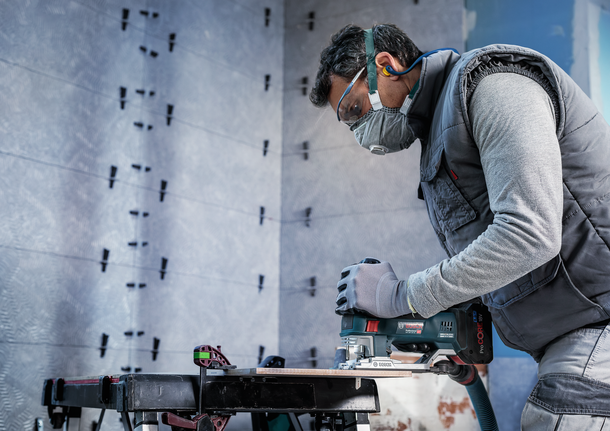 PRO Soft Tile T130RF 線鋸片,83 mm,3 件 一名配戴安全設備的人員在工作台上使用曲線鋸切割木材。