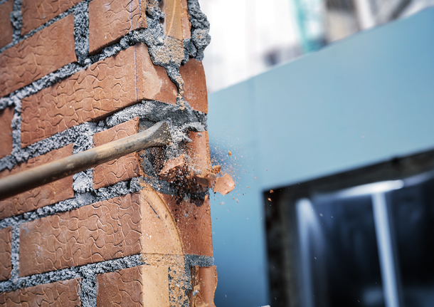 鑿破磚牆，導致碎片散落。