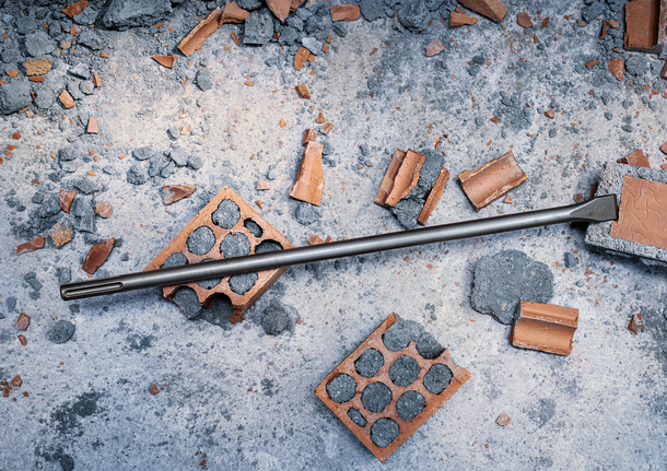 鑿子鑽頭躺在碎磚和混凝土碎片上。