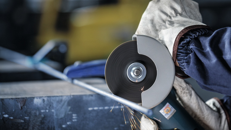 配戴安全設備的人員使用角磨機切割金屬管路。.