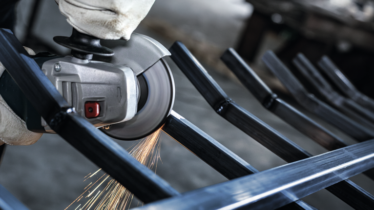 配戴安全設備的人員研磨金屬棒，產生火花。.