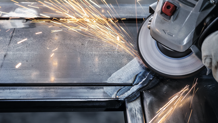 配戴安全設備的人研磨金屬，產生明亮的火花。.