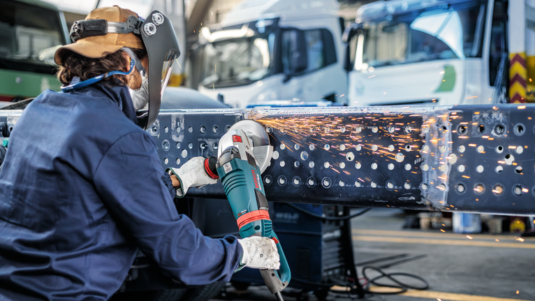 配戴安全設備的人研磨金屬梁，產生火花。.