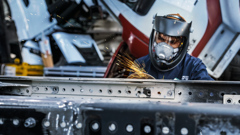 配戴安全設備的人研磨金屬，產生明亮的火花。.