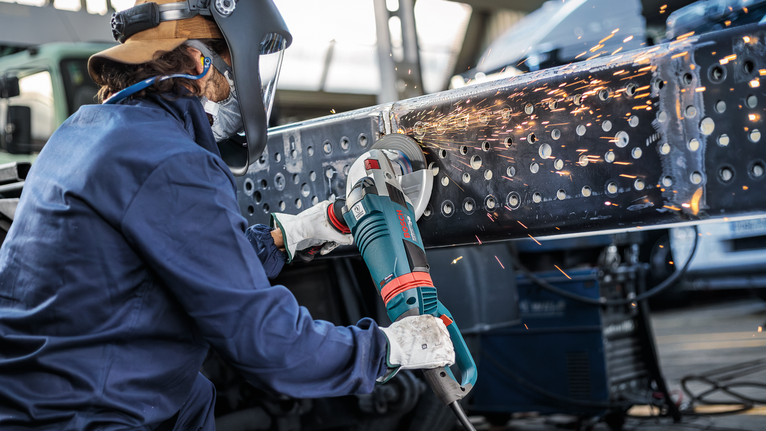 配戴安全設備的人研磨金屬梁，產生明亮的火花。.