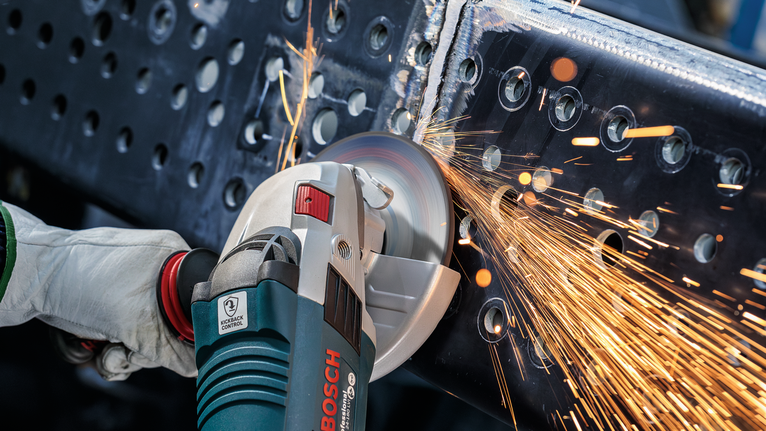 配戴安全設備的人研磨金屬梁，產生火花。