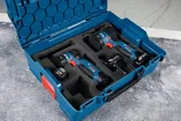 無線電動工具和電池整齊地放在工作台上的藍色手提箱中。