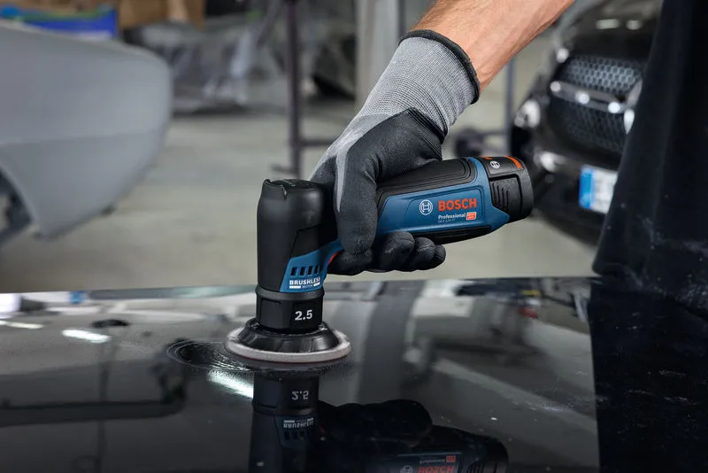 一名佩戴安全設備的人員使用隨機軌道砂光機拋光汽車錶面。.