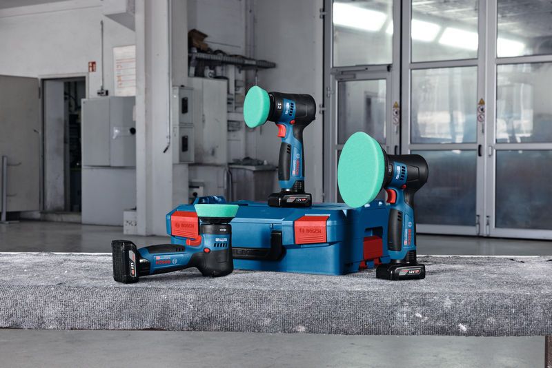 車間裡的一個藍色箱子上放置著三台配有綠色拋光墊的無線拋光機。.