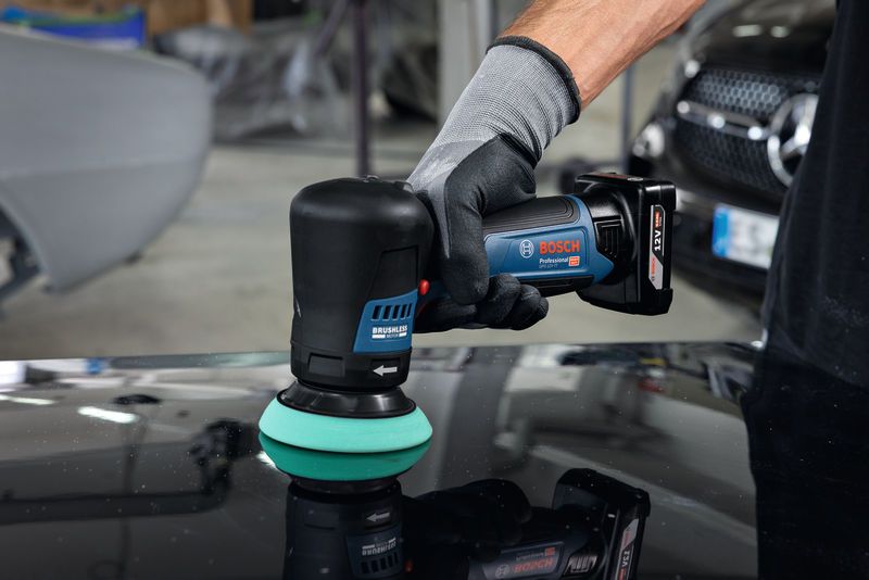 一名配戴安全設備的人員正在使用無線拋光機拋光汽車錶面。.