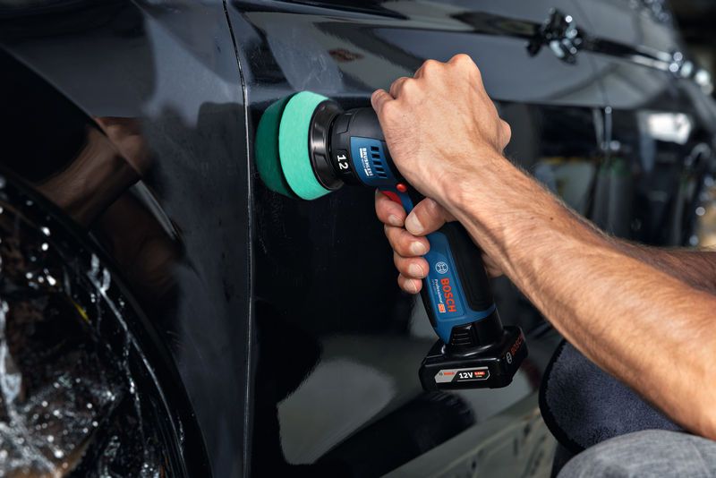 GPX 12V-77 一個人使用無線拋光機拋光黑色車門。.