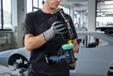 一名配戴安全設備的人員在汽車修理廠內為拋光機上拋光。