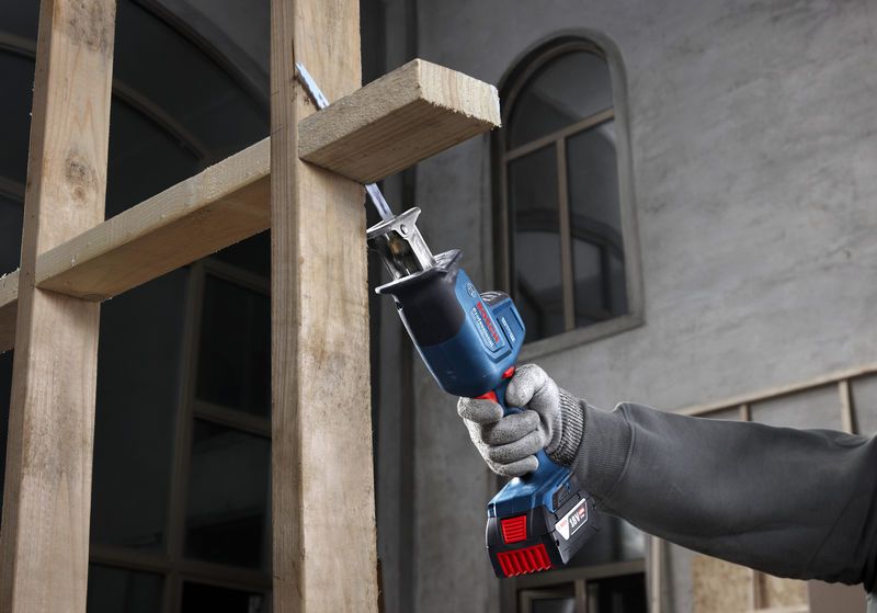 一名配戴安全設備的人員使用往復鋸切割木樑。.