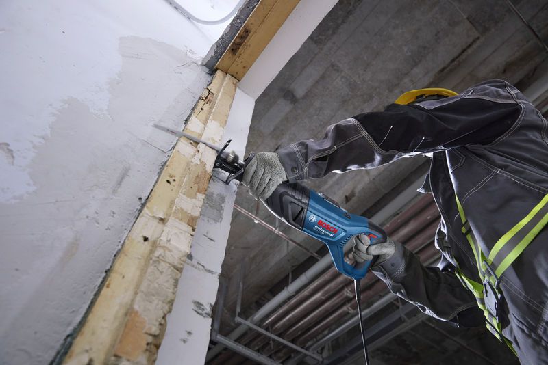 一名配戴安全設備的人員使用往復鋸切割牆壁。.