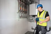 一名配戴安全設備的人員在牆管附近設置雷射調平工具。