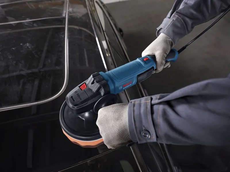 一名佩戴安全設備的人員正在使用電動拋光機拋光汽車車頂。.