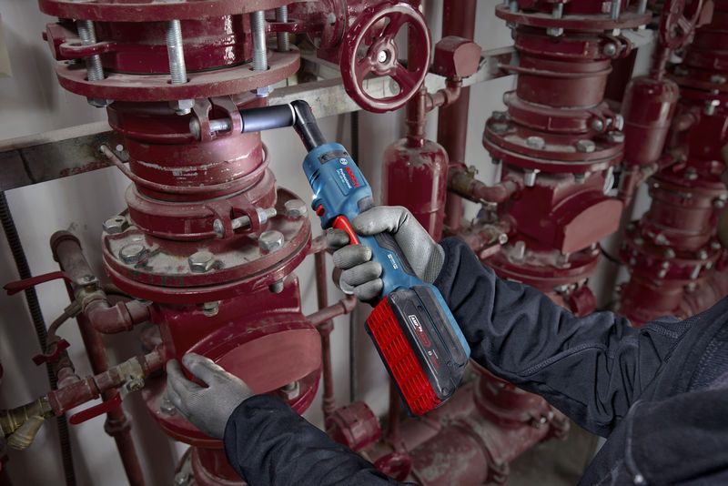 一名配戴安全設備的人員正在使用無線棘輪扳手擰緊管道螺栓。.