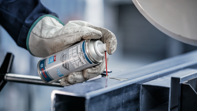 配戴安全設備的人員將潤滑劑噴灑到金屬樑上。