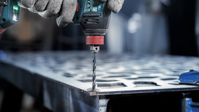 配戴安全設備的人員在金屬板上鑽孔。