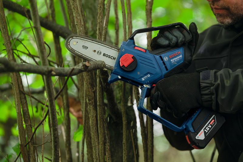 一名配戴安全裝備的人員正在使用無線修枝鋸修剪樹枝。.