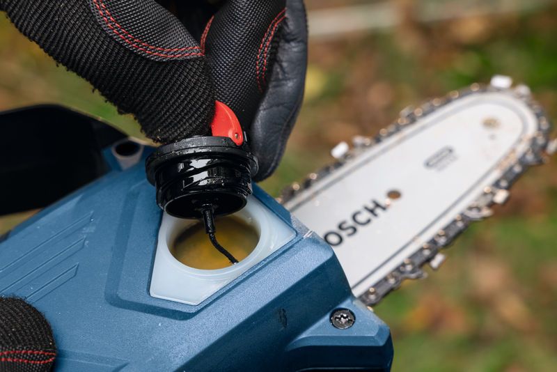 配戴安全裝備的人員打開無線修枝鋸刀片附近的油蓋。.