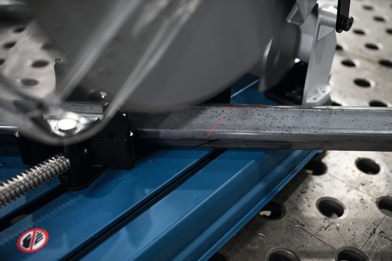 GCD 18V-355 帶有紅色導線的金屬切割鋸在穿孔工作台上切割鋼筋。.