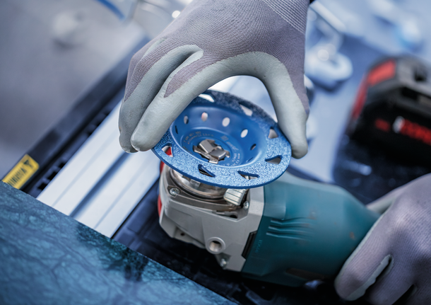 配戴安全設備的人員將砂輪安裝到電動工具上。.