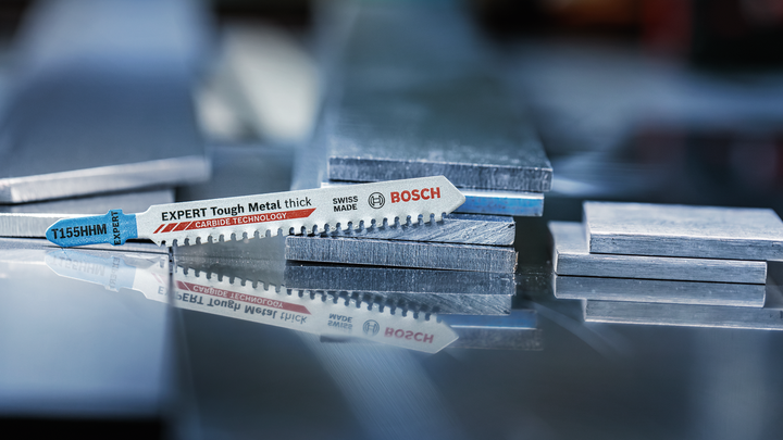 Object #200559112: 7478951_app_web_02 拼圖鋸刀片放置在反射表面上的堆疊金屬板上。